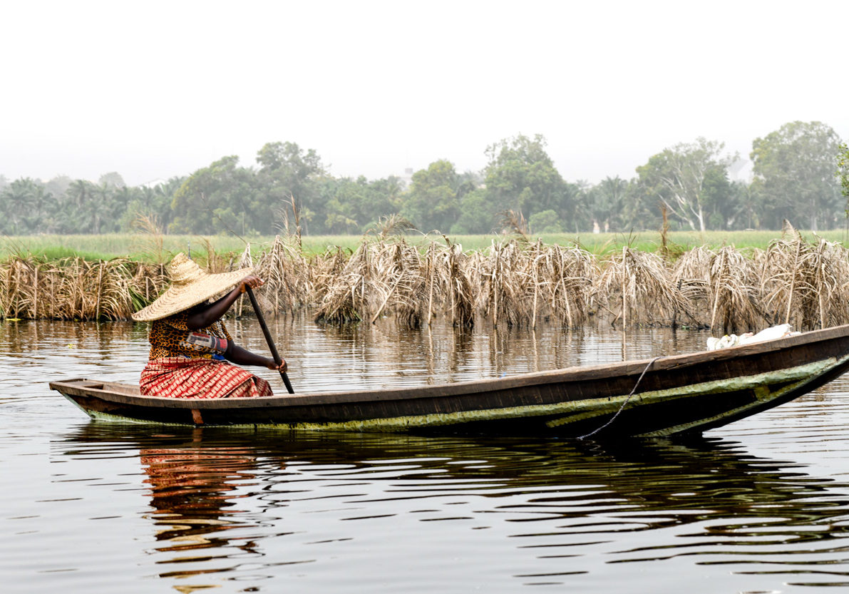 Africa, West Africa, Benin, Lake Nokoue, Ganvié. Woman rowing in the back of a pirogue outside the lakeside town of Ganvié on Lake Nokoue.